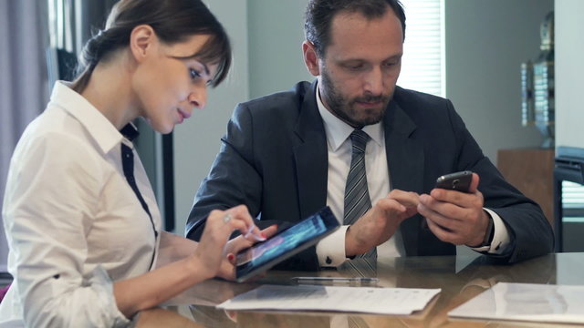 Businesspeople working with smartphone and tablet by table in the office
