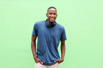 Young  man smiling with headphones against green background