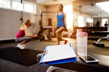 Gym details, women exercising, clipboard, water bottle, smart ph
