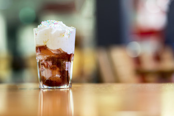 Dessert, chocolate ice cream in a glass. Fresh ice cream in a glass cup covered with whipped cream and sprinkled with icing. 