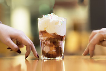 Dessert, chocolate ice cream in a glass. Fresh ice cream in a glass cup covered with whipped cream and sprinkled with icing. 
