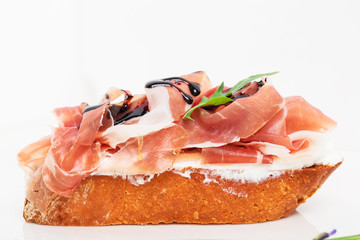 Prosciutto bruschetta with ricotta and arugula.