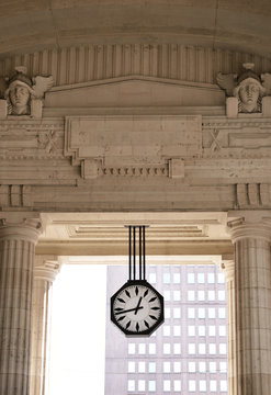 The clock  of classical passage with columns and antique heads and white sky background