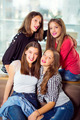 Portrait of four young women sitting at the table in the cafe, selective focus