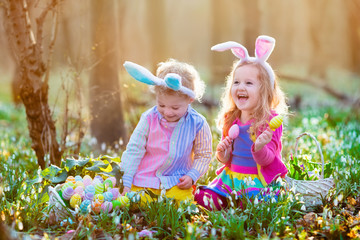Kids on Easter egg hunt in blooming spring garden.