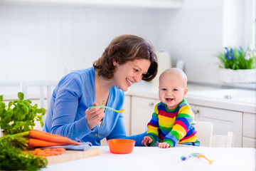 Mother feeding baby first solid food