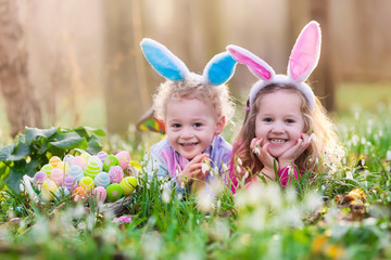 Kids on Easter egg hunt in blooming spring garden