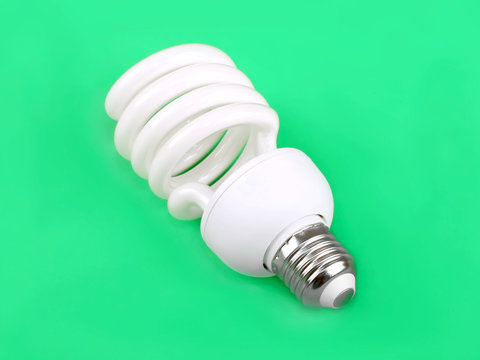 Energy saving fluorescent light bulb on green background