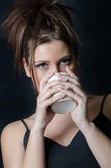 Beautiful face of a lady and hairdo with bangs holding a cup and drinking