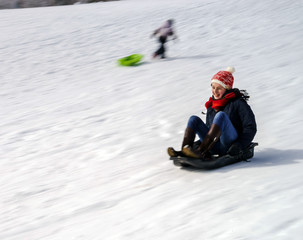 Fototapeta na wymiar Teenage girl sledding from the hill