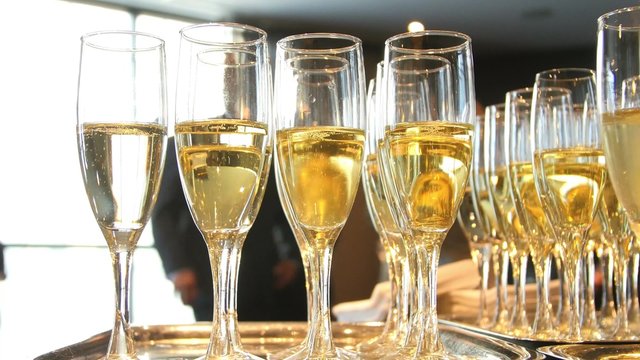 Champagne glasses sit on serving trays as people mingle.