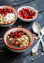 Healthy Breakfast - yogurt with homemade granola and pomegranate on a dark wooden board.
