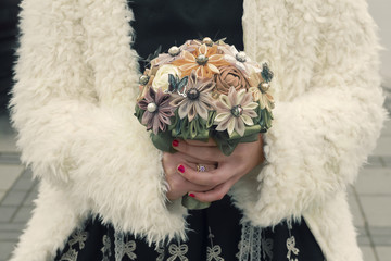 Women hands holding a handmade bouquet of artificial flowers. Celebration concept.