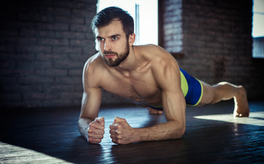 Fototapeta na wymiar Sport. Young athletic man doing push-ups. Muscular and strong guy exercising.