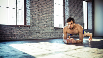 Sport. Young athletic man doing push-ups. Muscular and strong guy exercising.