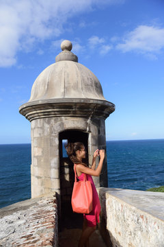 Puerto Rico woman taking pictures with smartphone at Old San Juan Fort Castillo San Felipe Del Morro. Asian tourist on her american travel visiting a famous landmark during summer vacations.