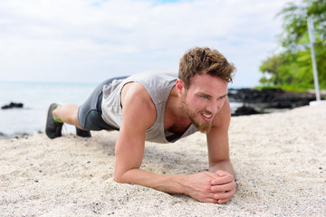 Crossfit training fitness man doing plank core exercise working out his midsection muscles. Fit athlete fitness cross training planking exercising outside in sand on beach.