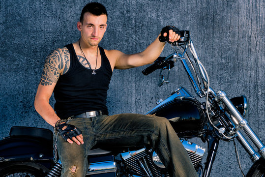 Tough, tattooed fighter with his bike in chopper-style