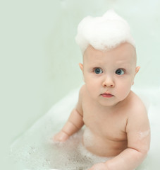 The kid in the bathroom washing her head with shampoo foam