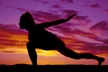 silhouette of a woman doing a lunge in the sunset