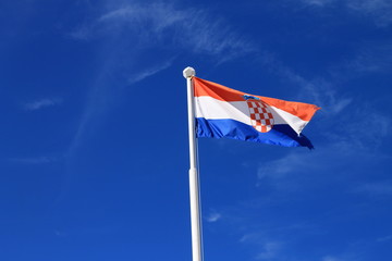 Flag of Croatia with flag pole waving in the wind with blue sky in background