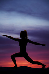 silhouette of a woman in lunge with arms out in sunset