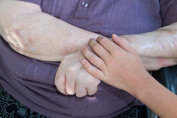 Old and young. Child's hand on arm of a mature woman