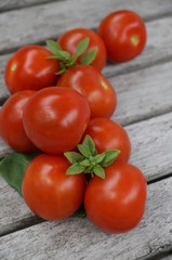Red tomatoes and green basil on a wooden table