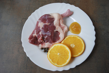Fresh duck legs with orange and honey on the white plate.