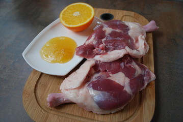 Fresh duck legs with orange and honey on a wooden board.