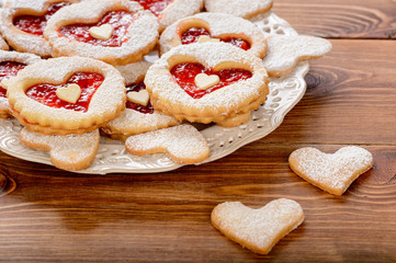 Shortbread cookies in the shape of heart with strawberry jam on wooden table.