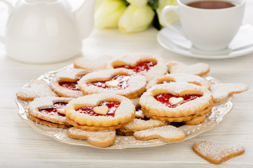 Shortbread cookies in the shape of heart with strawberry jam on wooden table.