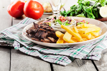 Grilled meat with French fries and fresh vegetables