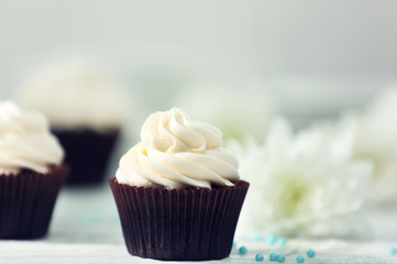 Chocolate cupcakes and flowers on a table
