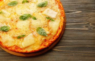 Tasty pizza decorated with basil  on wooden background, close up