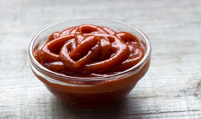 Bowl of tomato ketchup  on wooden background