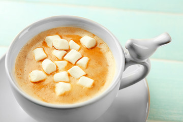 Cup of hot cacao with marshmallow on blue table