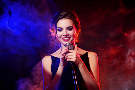 Young beautiful woman singing in colourful smoke, close up