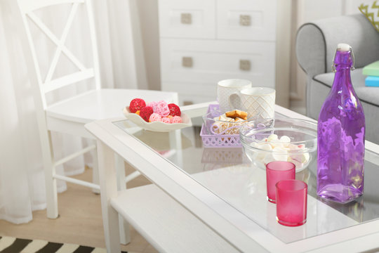 Low table with purple bottle, sweets and two cups in living room