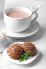 Cup of cocoa with chocolate chip cookies and mint on light background