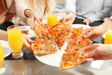 Friends hands holding hot pizza, close up