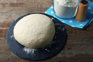 Fresh prepared dough on a wooden board, close up