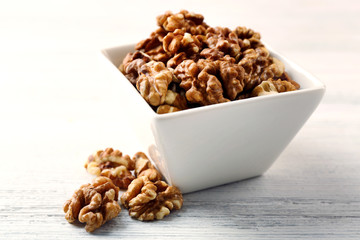 Walnut kernels in the bowl on white wooden background