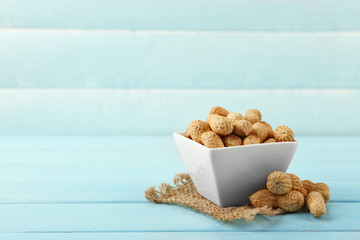 Peanuts in the bowl on blue wooden background