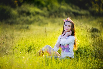 Young beautiful girl sitting on the grass and smiling