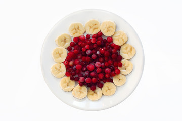 Замороженная клюква, окруженная кусочками банана на белой тарелке