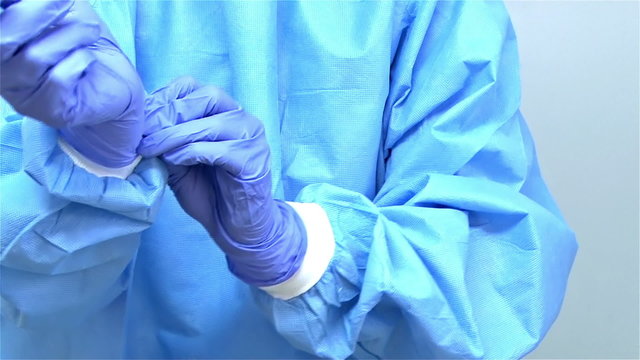 A surgeon preparing for surgery puts on gloves