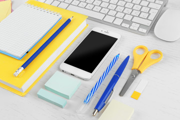 Workplace with mobile phone, computer peripherals and stationery on light table