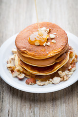 Stack of homemade pancakes with honey on wooden background.