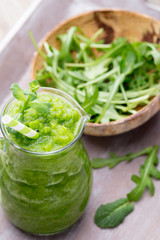 Rucola smoothie, on the grey  background.